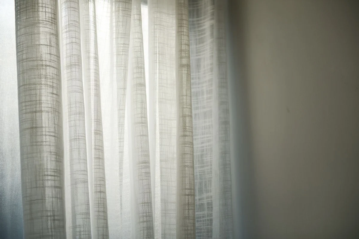Daylight filtering through sheer white curtains