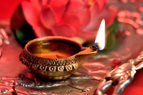 A lit diya standing on a metal tray