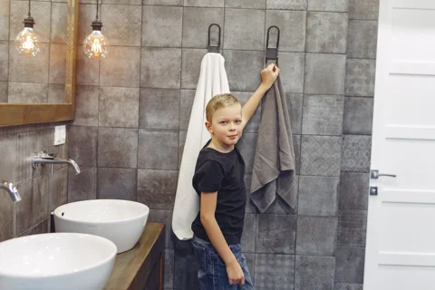 A child reaching for a bathroom hand towel
