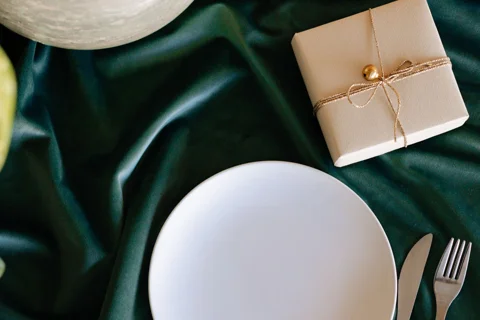 A gift package beside plates and a small plant