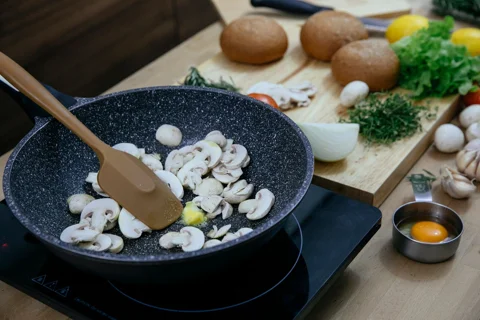Mushrooms cooking in a pan with a silicone spatula