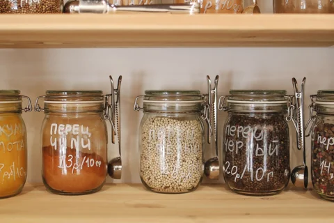 Labelled glass jars on wooden pantry shelves