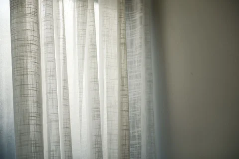 Daylight filtering through sheer white curtains