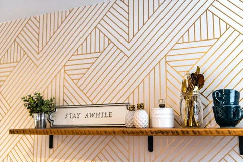 A small wall shelf holding cups and utensils
