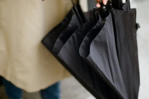 Hands opening a folded black umbrella